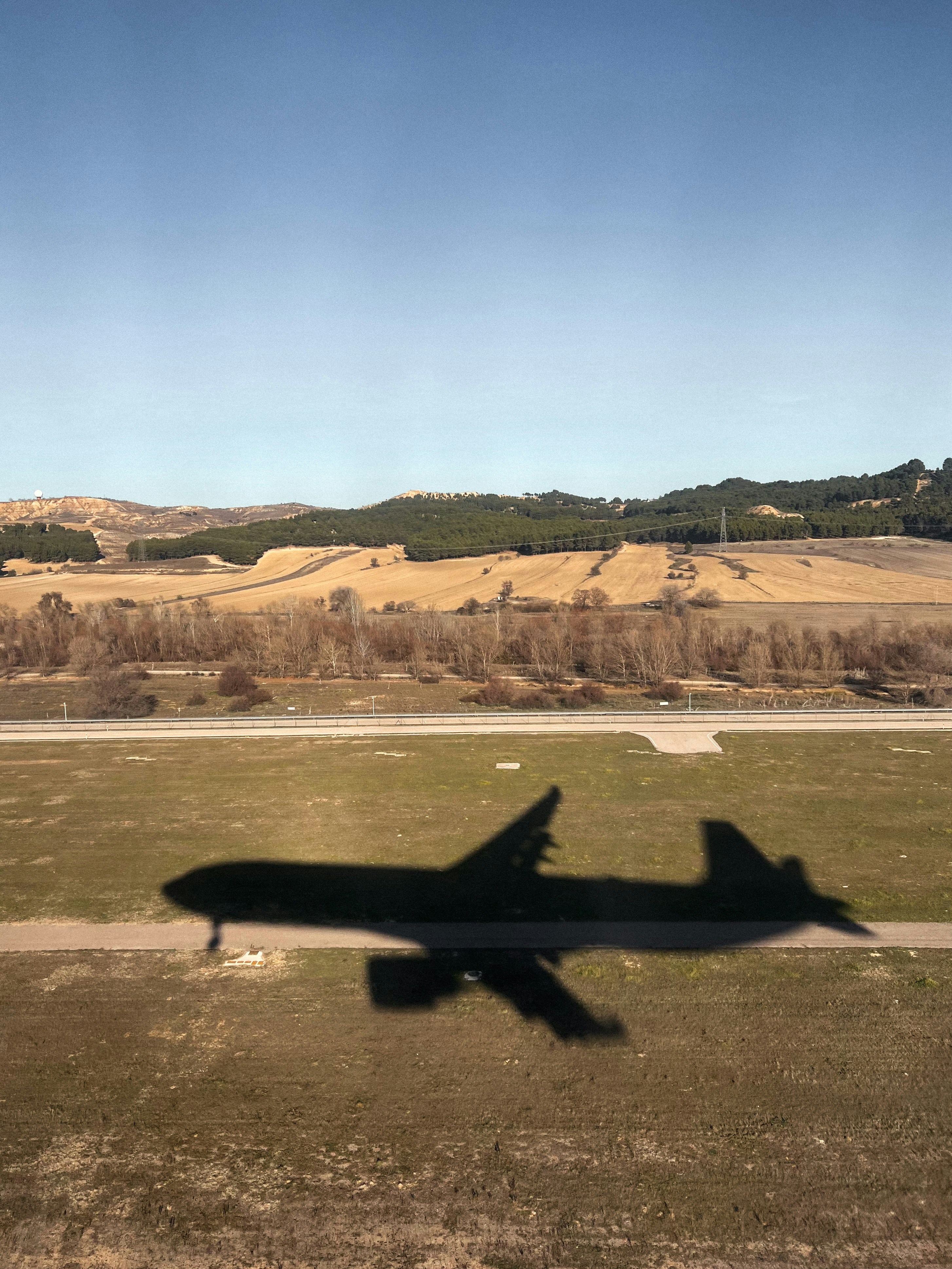 a large jetliner flying over a lush green field