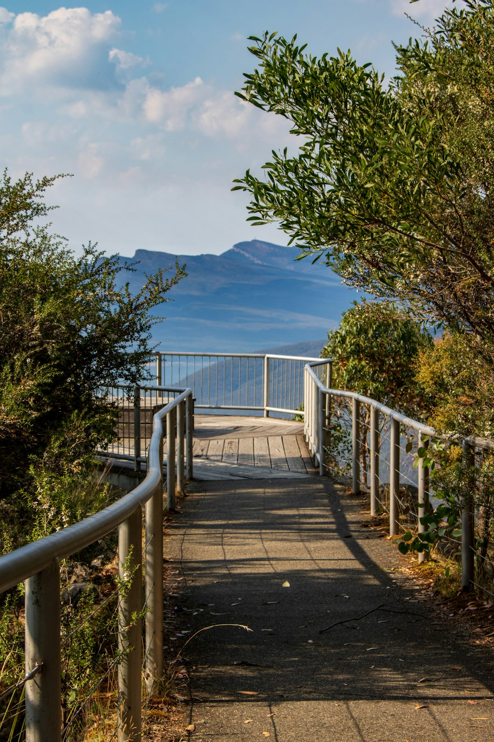 a walkway leading to the ocean with mountains in the background