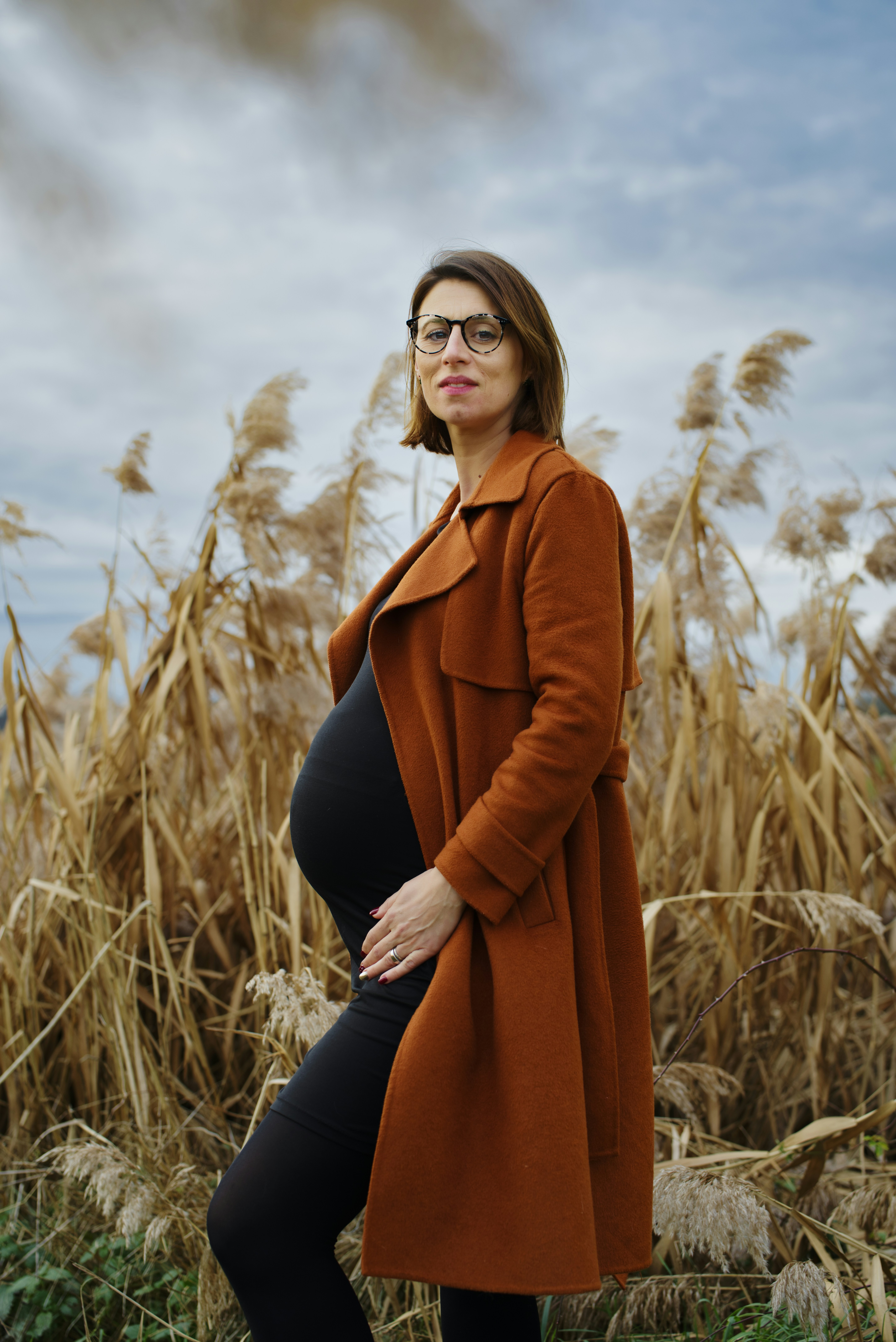 a pregnant woman standing in a field of tall grass