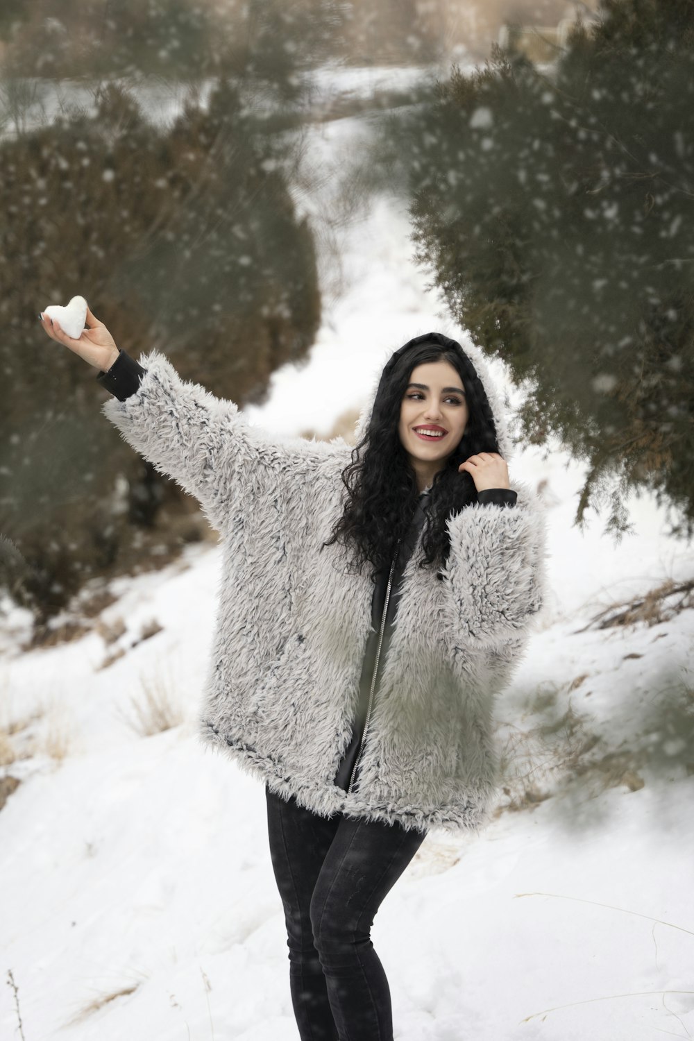 a woman standing in the snow holding a frisbee