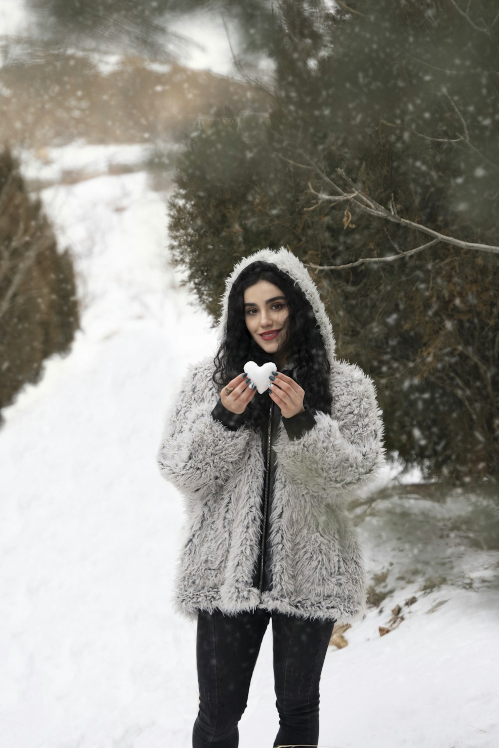 a woman standing in the snow holding a snowball
