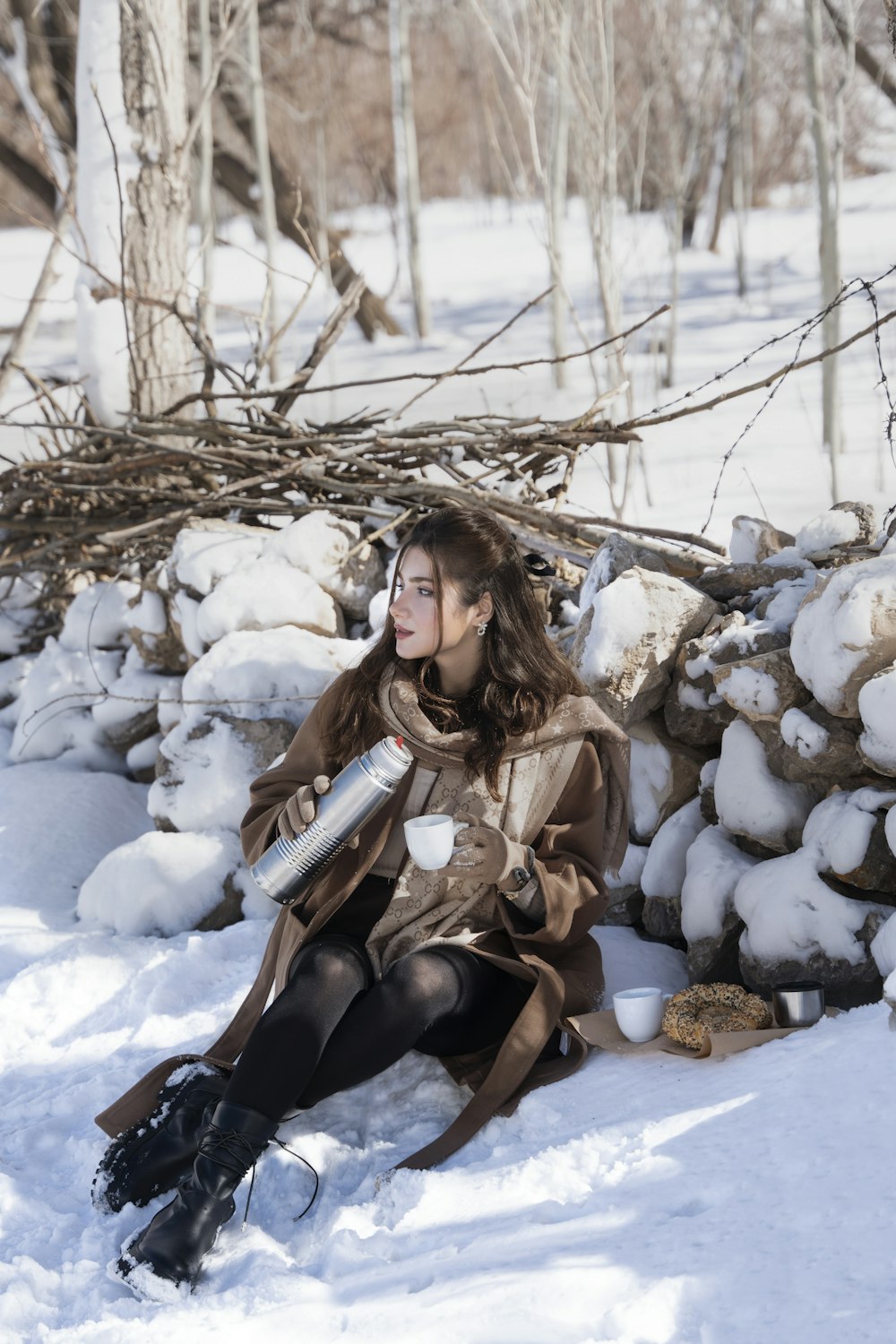 a woman sitting in the snow with a snowboard