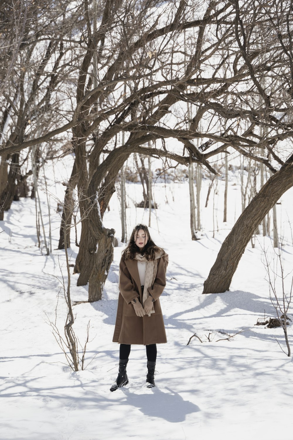 a woman standing in the snow in front of a tree