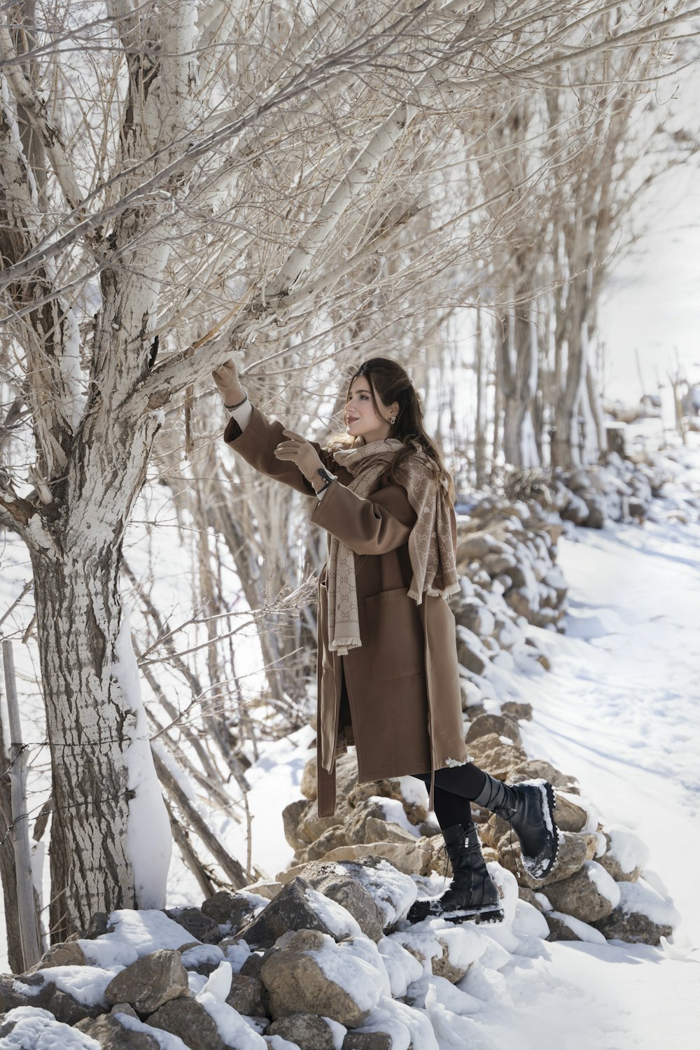 a woman standing next to a tree in the snow