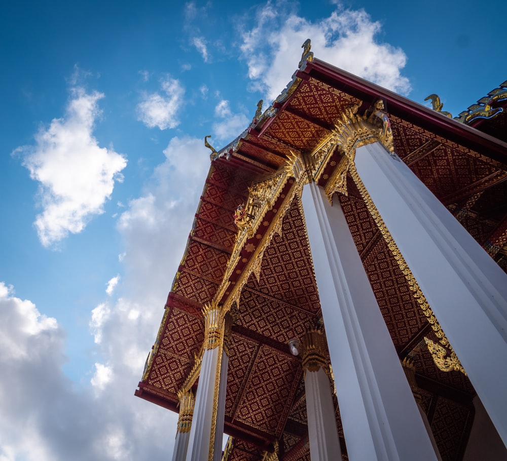 Un edificio blanco y dorado con columnas y un fondo de cielo