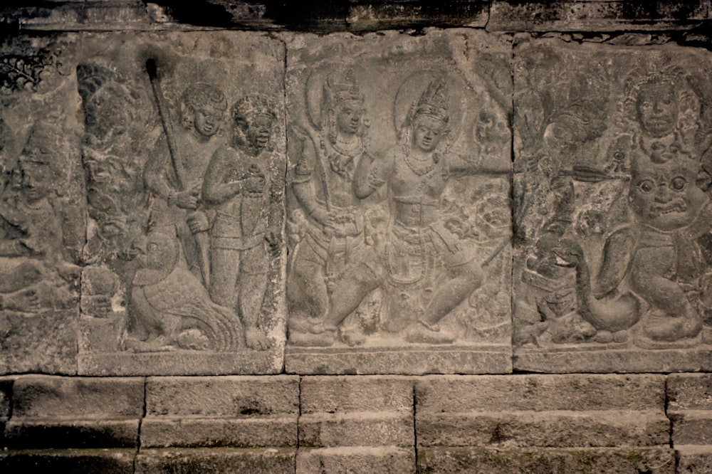 a stone wall with carvings of people and animals on it