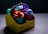 A brightly colored takeout box containing four cups with distinctive face-shaped lids. The box has a playful design with the text 'Shake & Shot To Go' on the side. Each cup is topped with a vibrant lid and straw, showcasing a whimsical approach to packaging.
