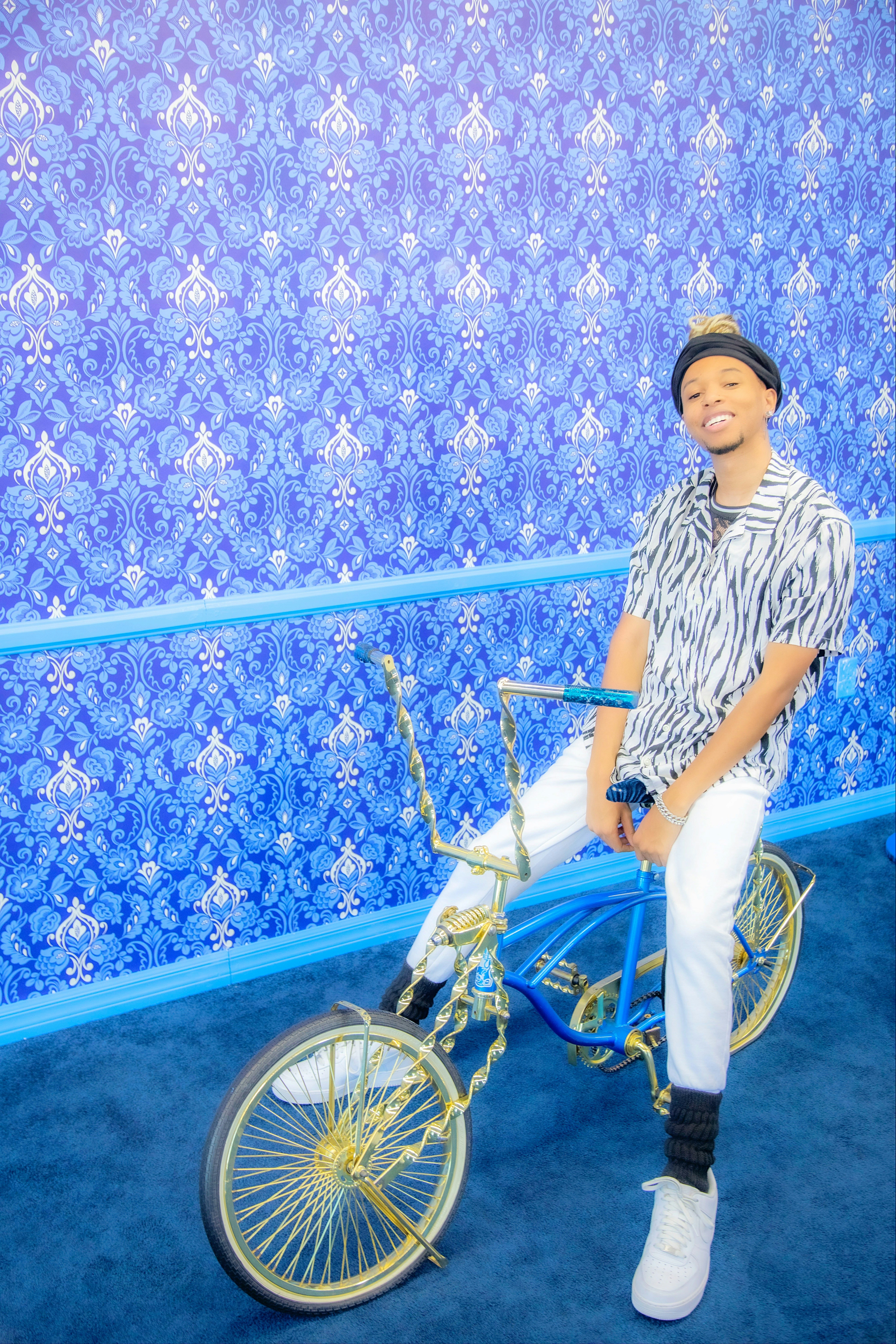 a man sitting on a bike in front of a blue wall