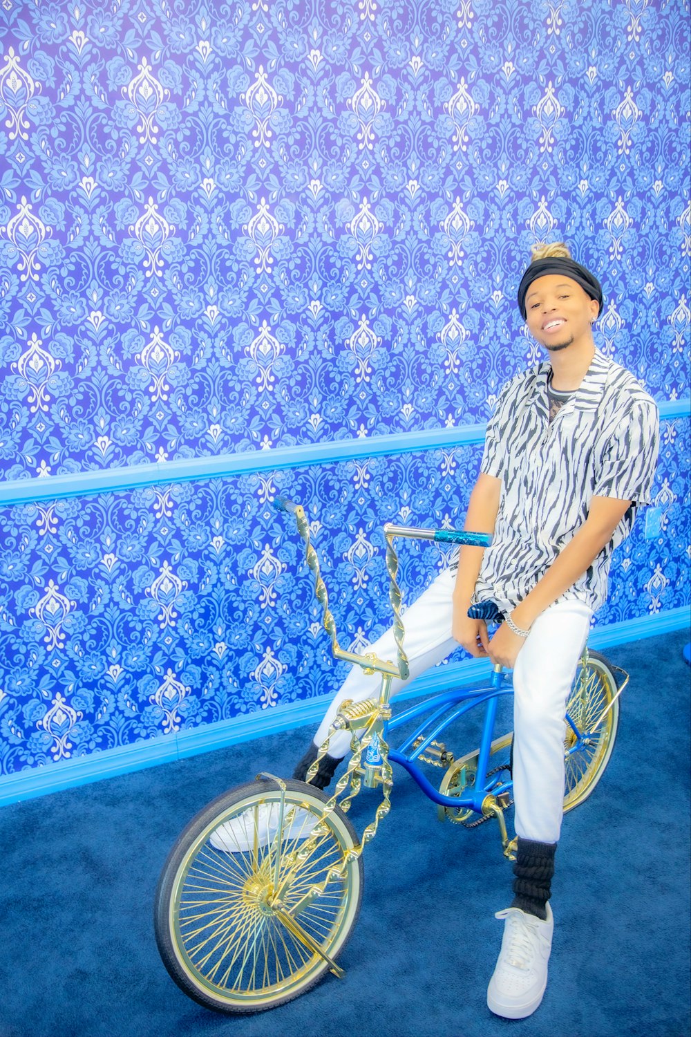a man sitting on a bike in front of a blue wall