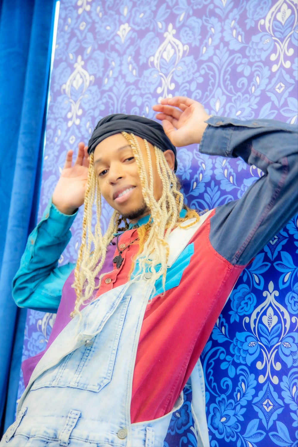 a woman with long blonde dreadlocks standing in front of a blue wall