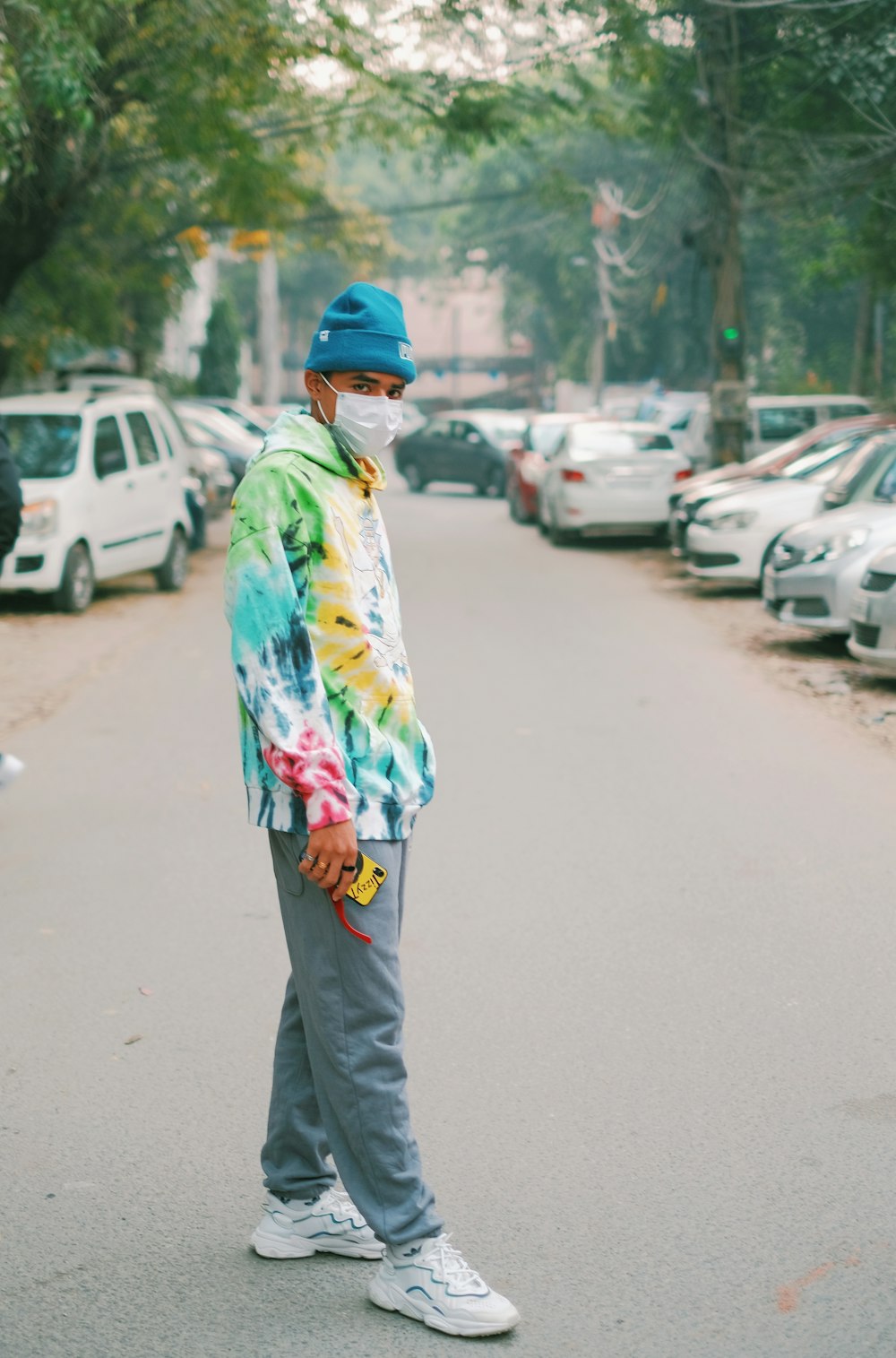 a man wearing a face mask standing in the middle of a street