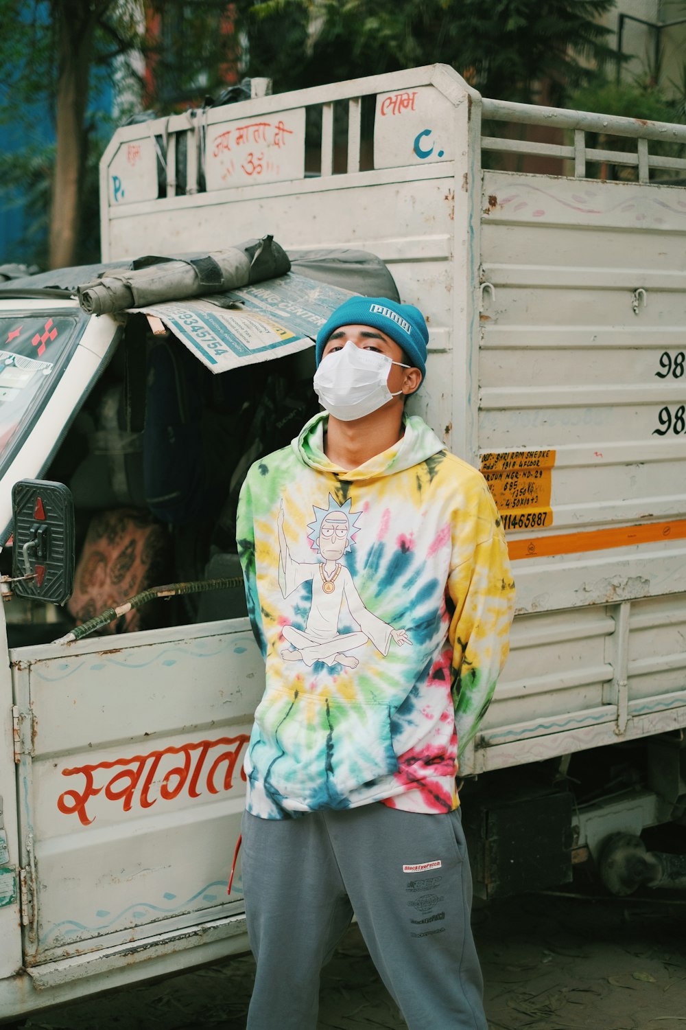 a man wearing a face mask standing in front of a truck