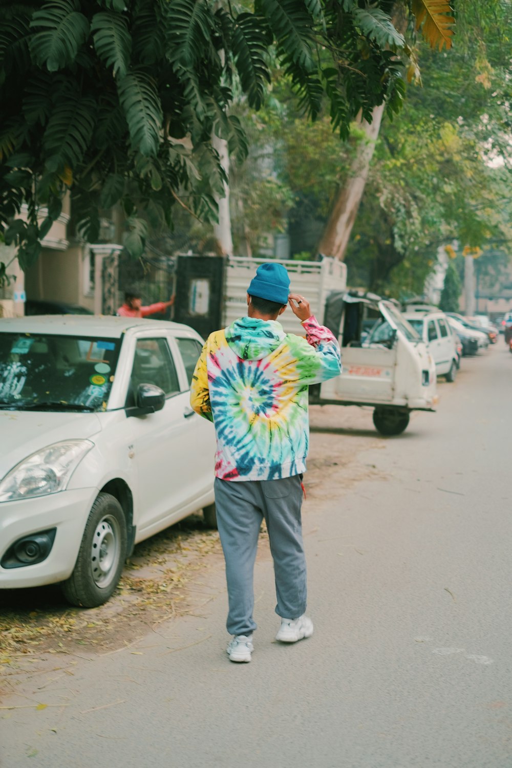 a man walking down a street next to parked cars