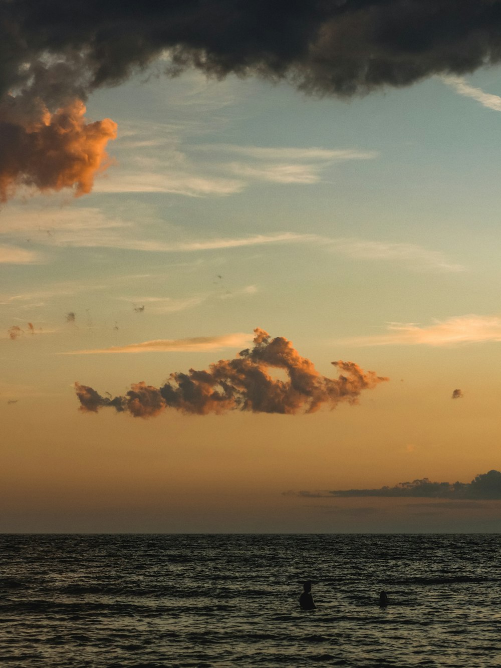 a couple of people in the water at sunset