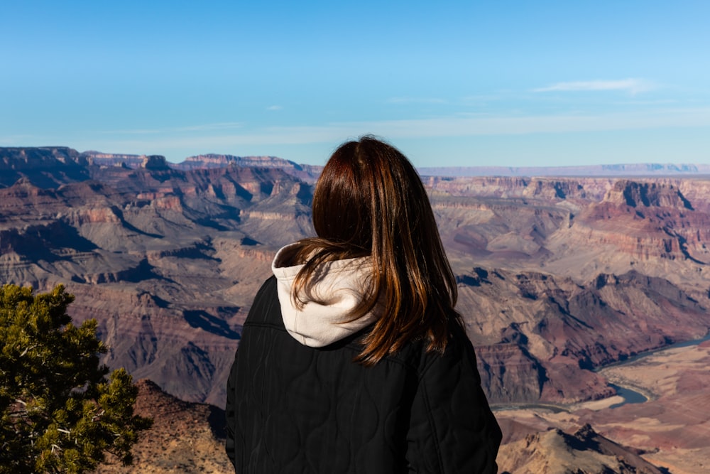a woman standing at the edge of a cliff overlooking a canyon