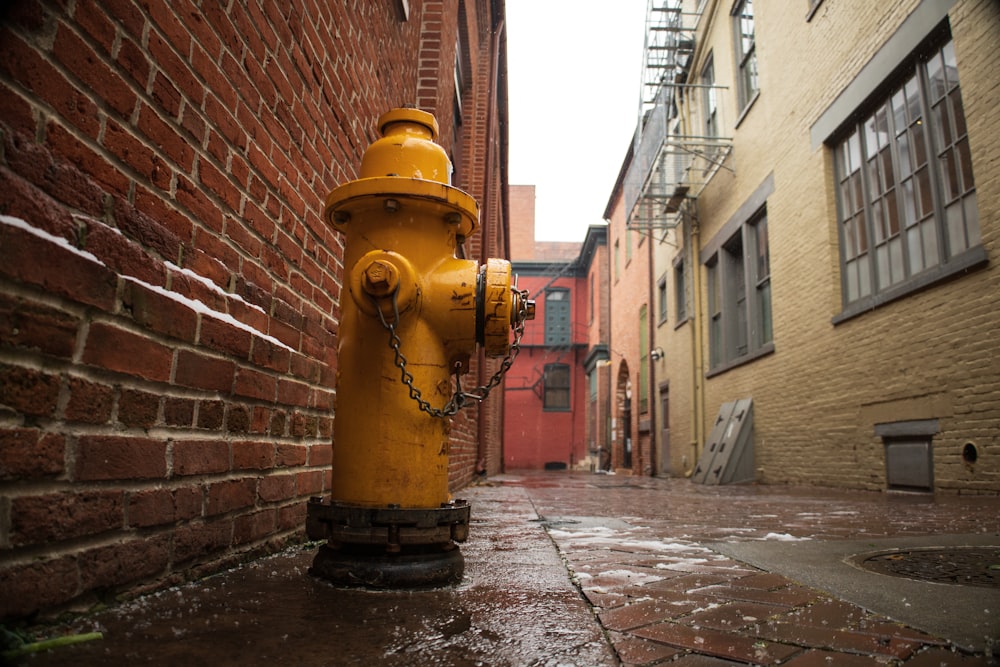 a yellow fire hydrant on the side of a building
