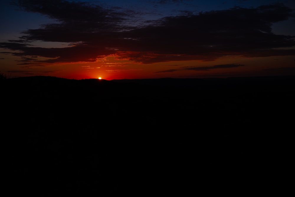 the sun is setting over the horizon of a field