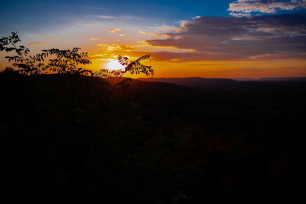 the sun is setting over the mountains and trees