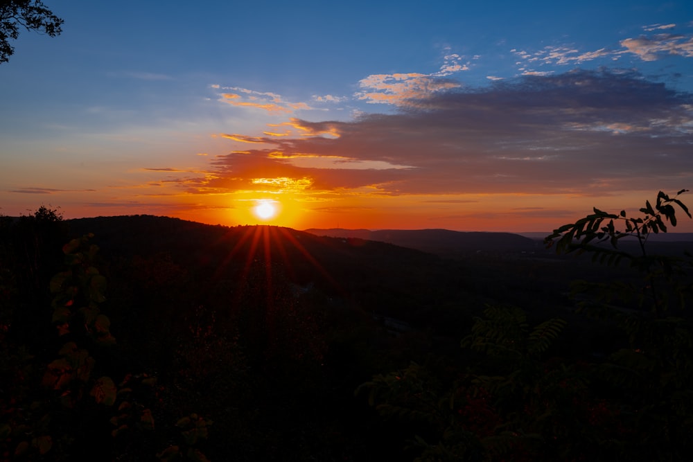 the sun is setting over a mountain range