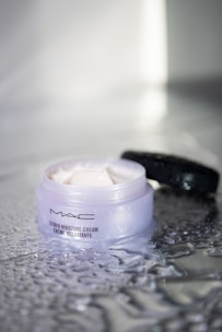 Close-up of a creamy moisturizer with a hint of shimmer on a sunlit surface.