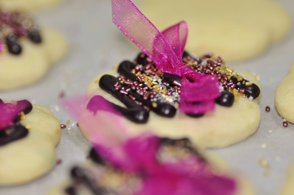 a close up of a tray of cookies with a pink ribbon