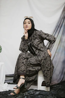 a woman sitting on a chair in a black dress