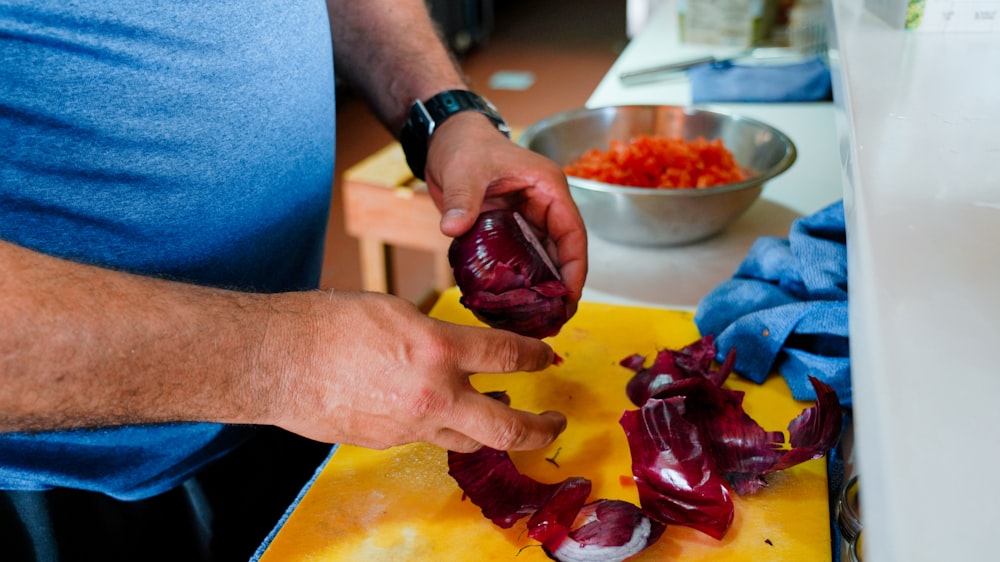 a man is peeling red onions on a cutting board