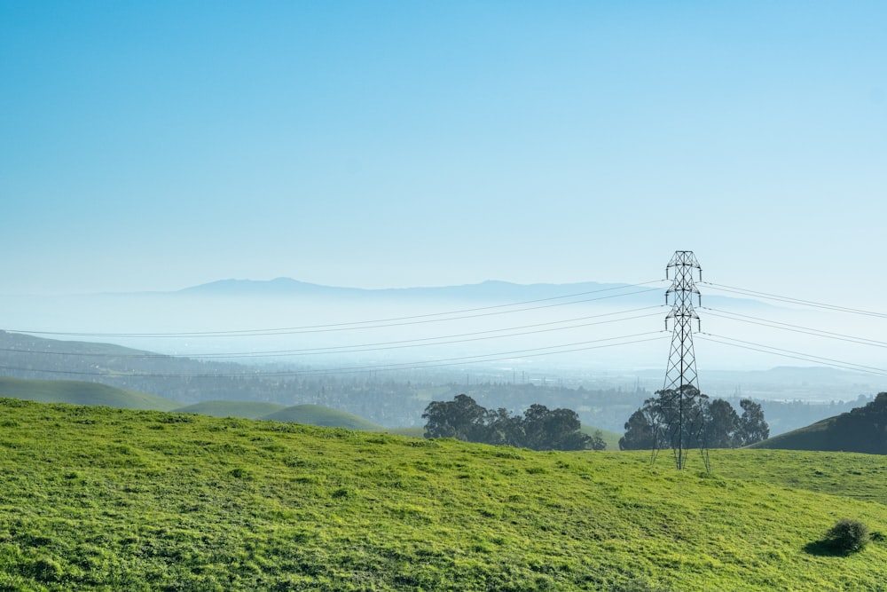 a grassy hill with power lines in the distance