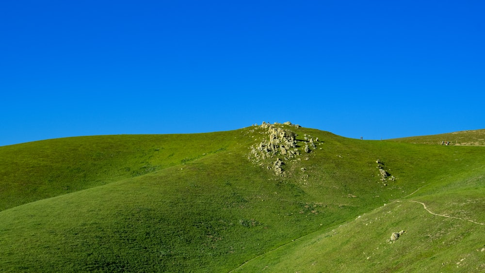 a grassy hill with a small house on top of it