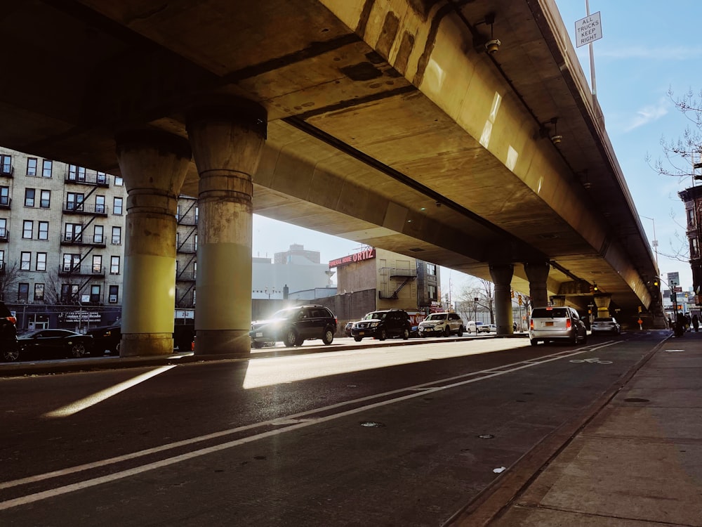 cars are driving under a bridge on a city street