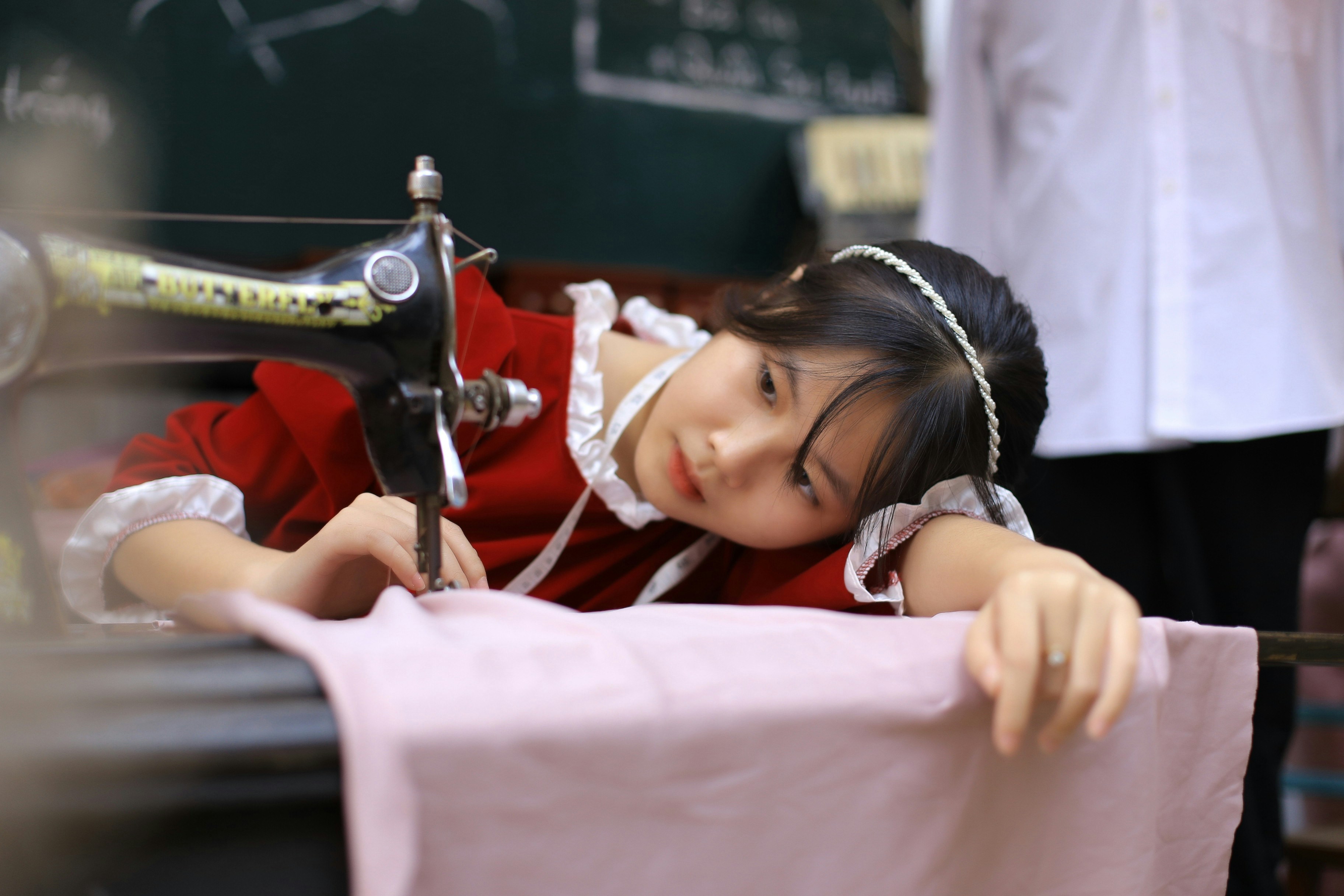 a young girl sitting at a table with a sewing machine