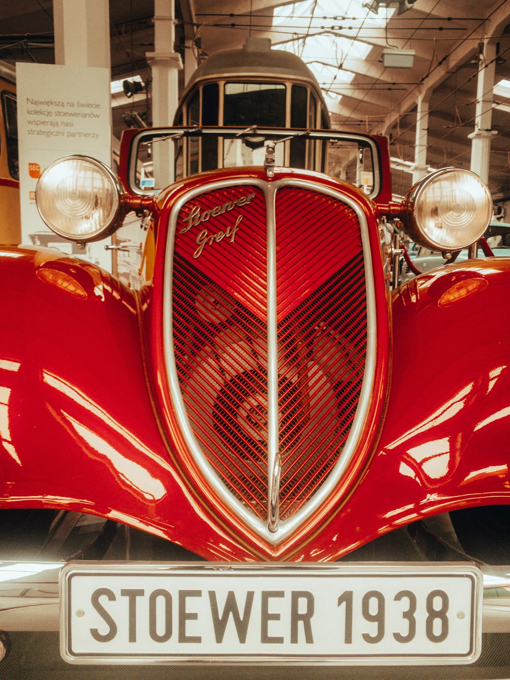 the front of a red vintage car with a white license plate