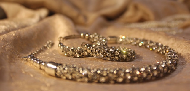 Close-up of a handcrafted gold necklace adorned with sparkling precious stones on a velvet background.