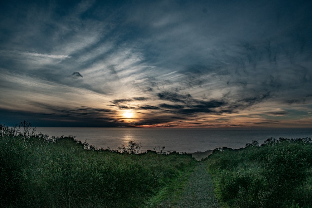 a path leading to the ocean with a sunset in the background