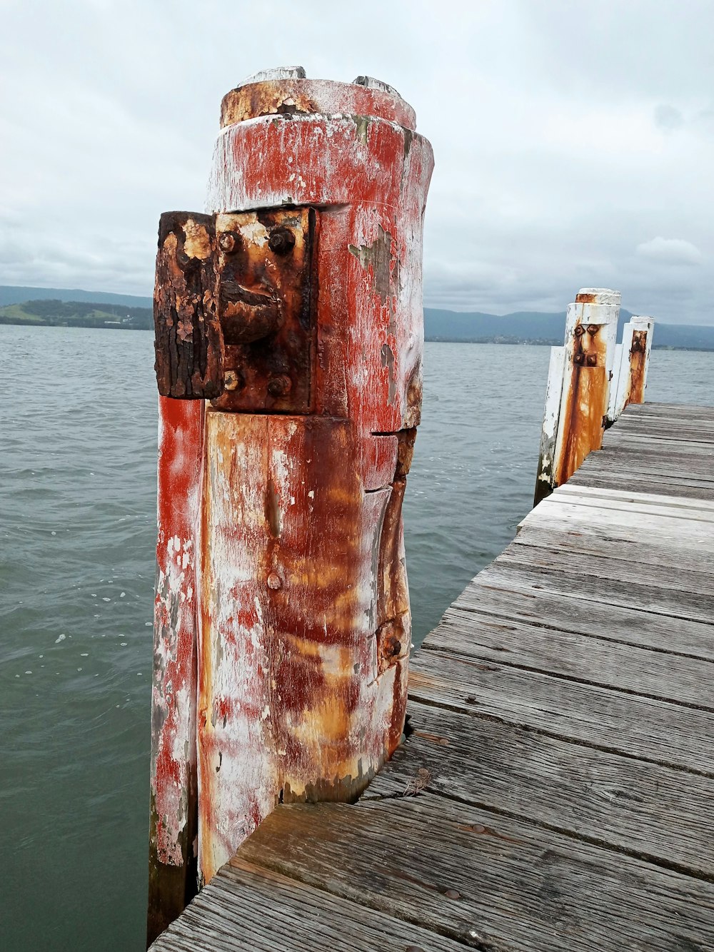 a rusted wooden dock with water in the background