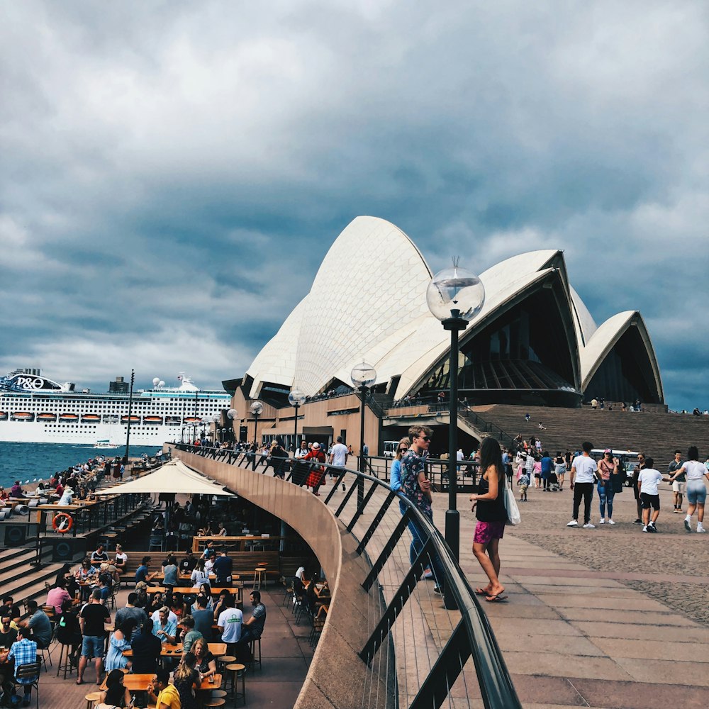 a crowd of people standing around a building near the water