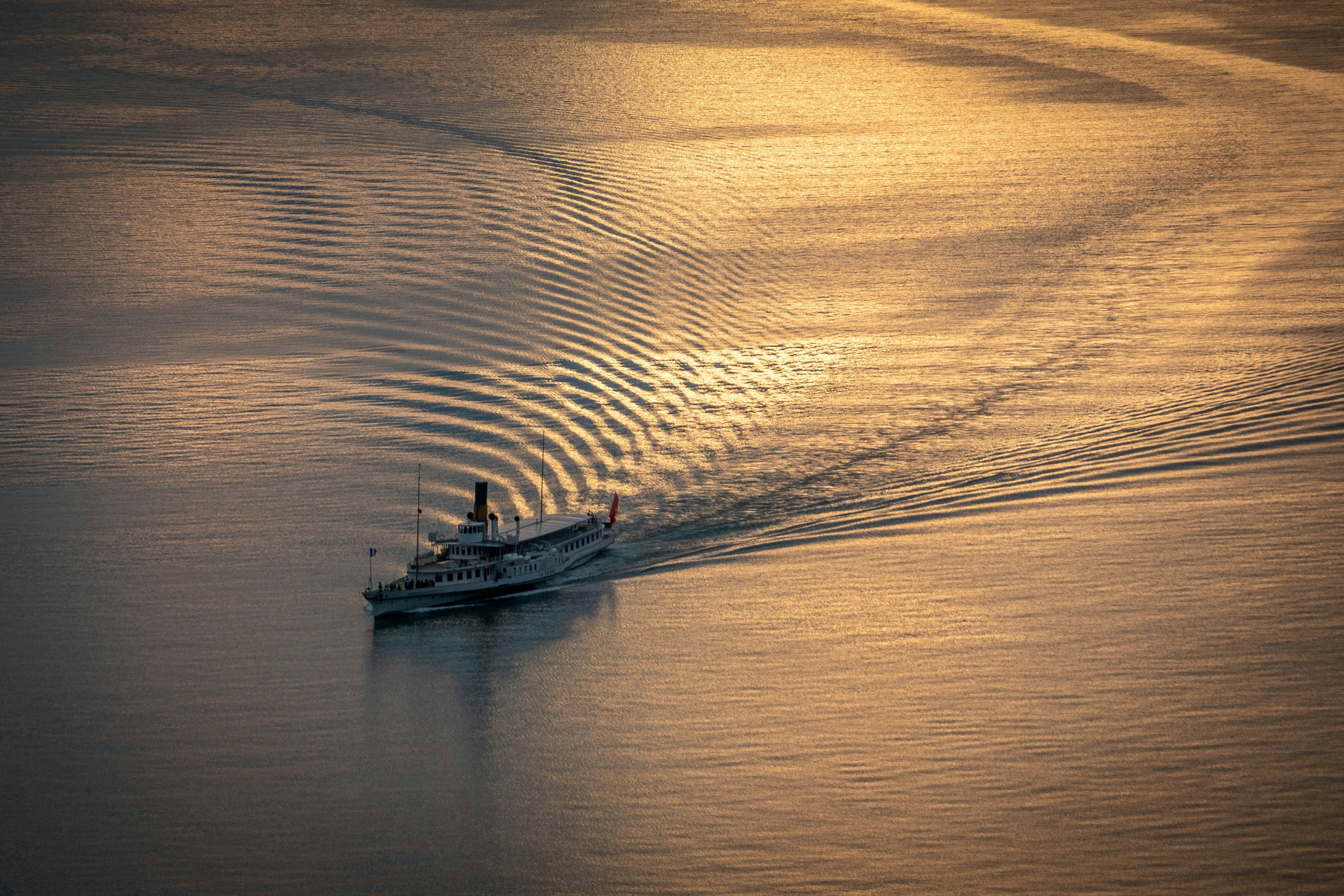 a boat traveling across a large body of water, Lac Léman</p><p>Navigation of “La Suisse” at Sunset time
