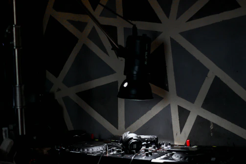 A DJ mixing tracks in a dimly lit room decorated with African textiles and neon lights.