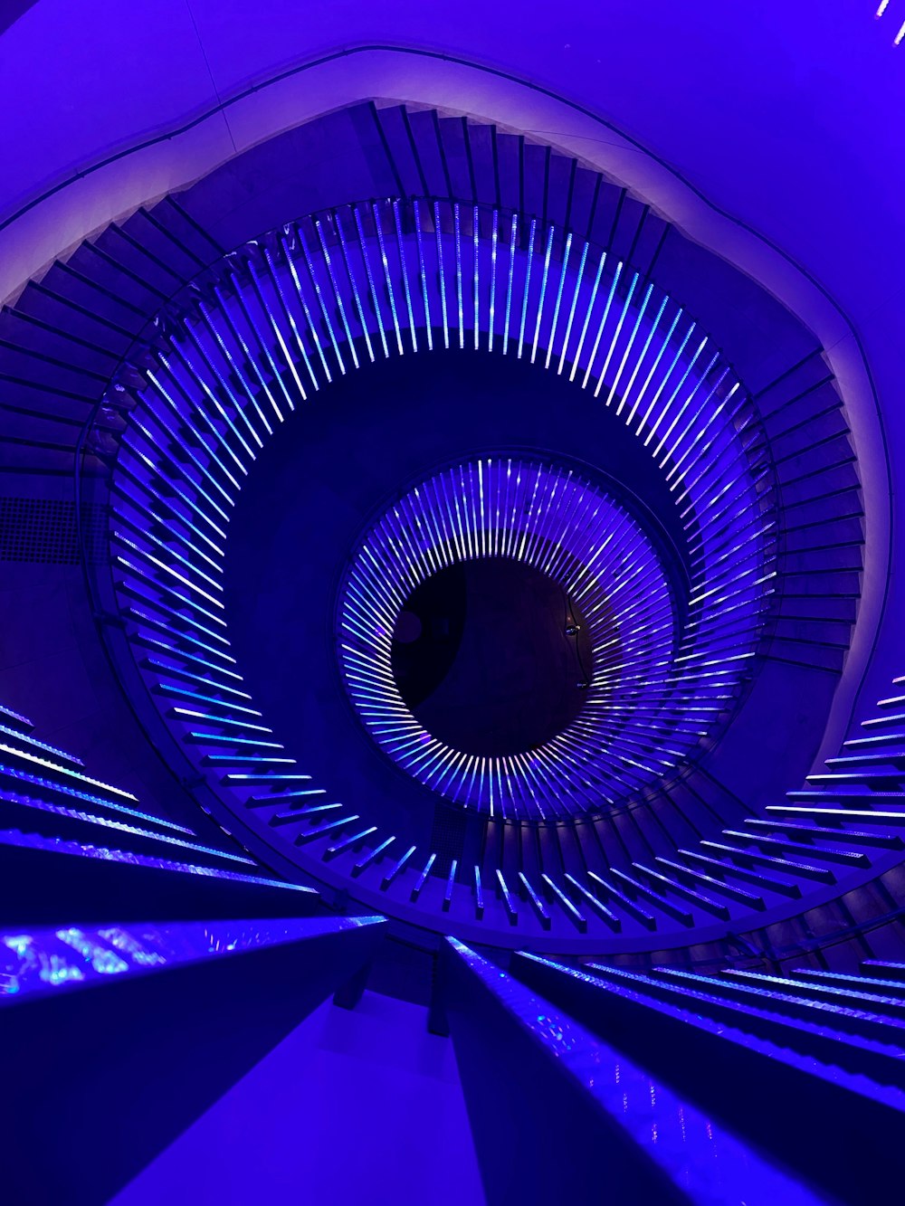 a spiral staircase in a building with blue lights