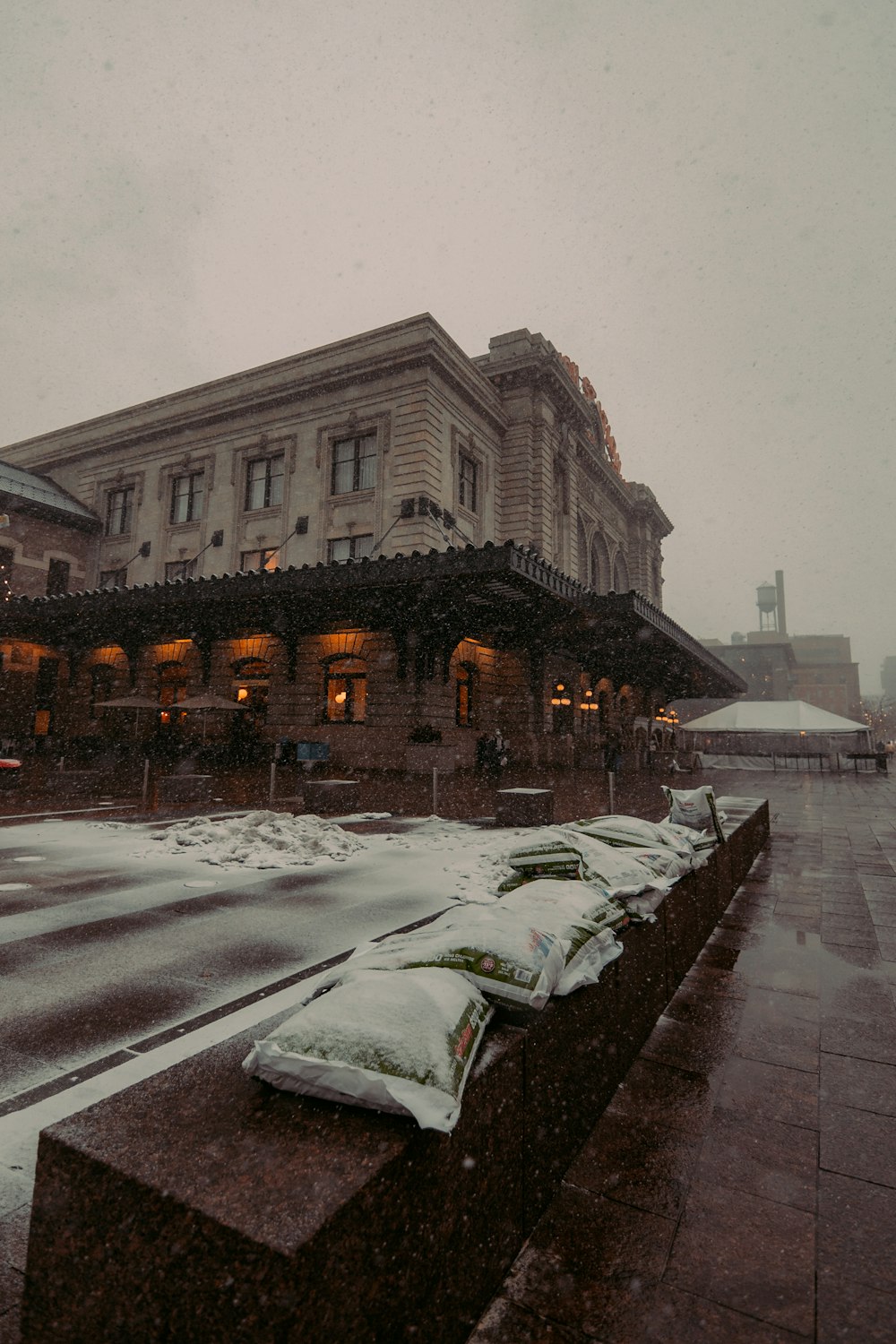 a snow covered bench in front of a building