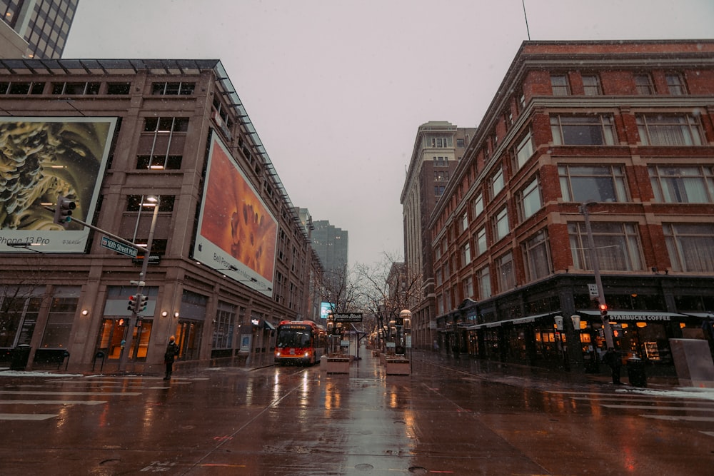 a wet city street with buildings and a bus