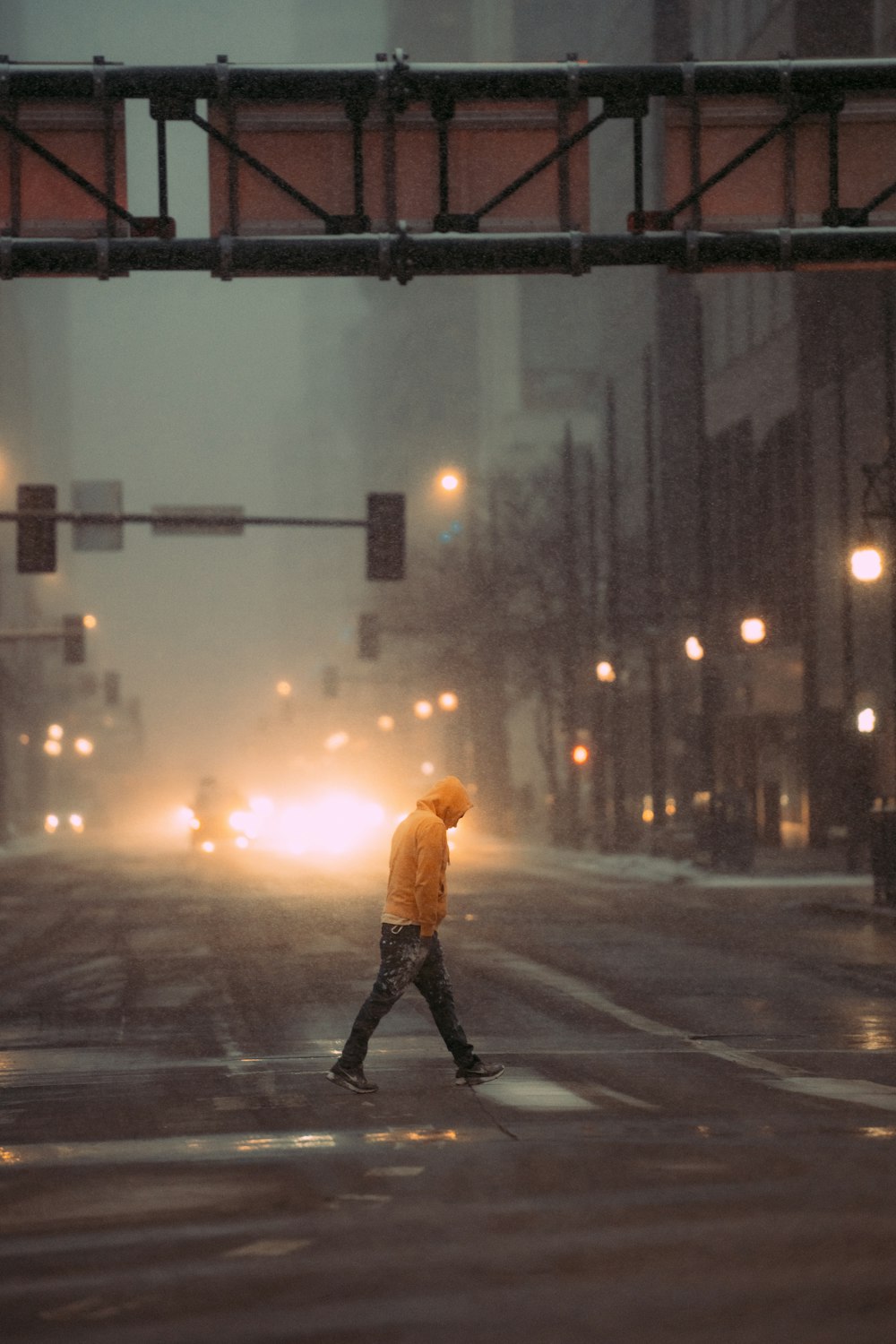 a man walking across a street in the rain