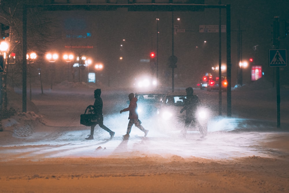 a group of people walking across a snow covered street