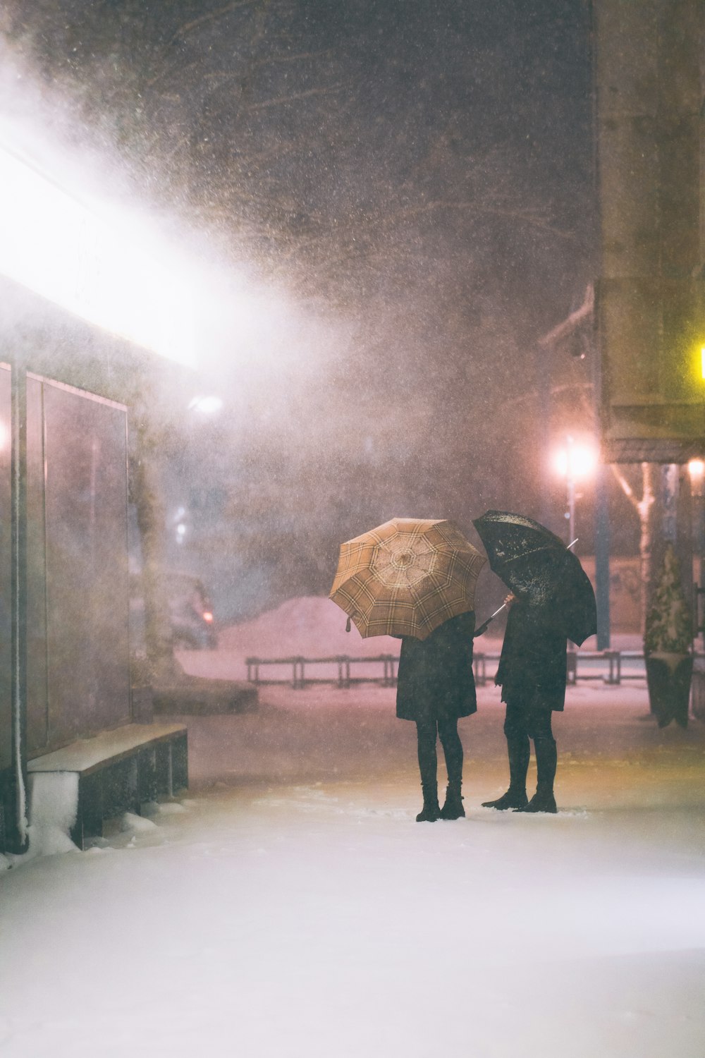 a couple of people standing next to each other holding umbrellas