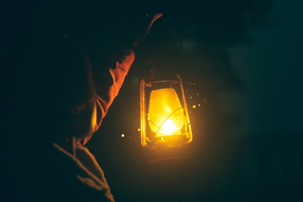 a person holding a lit lantern in the dark