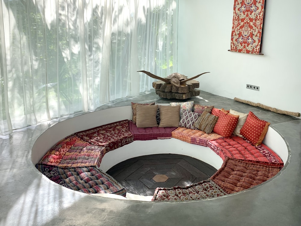 a circular couch with a lot of pillows on top of it