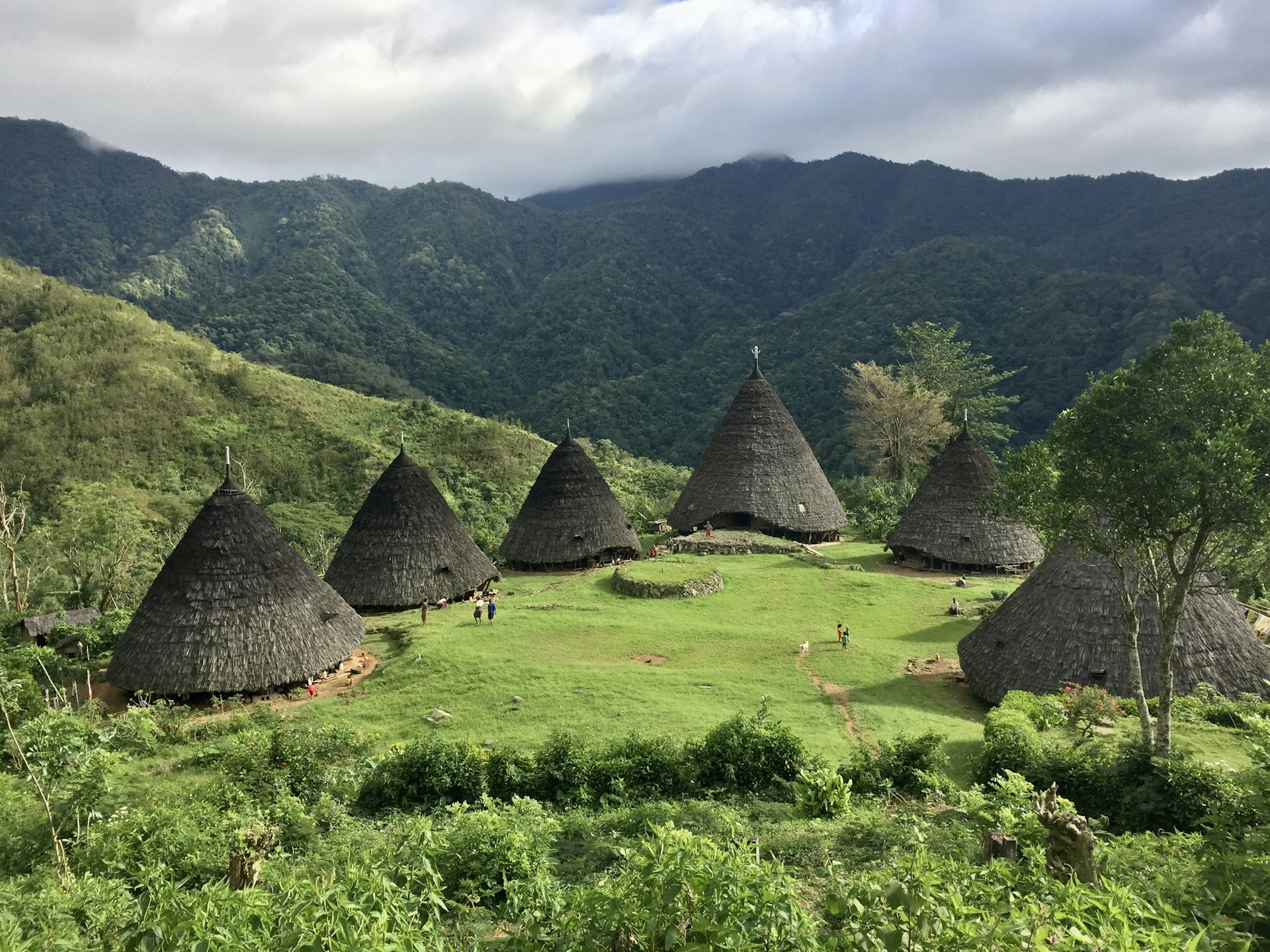 a group of huts sitting on top of a lush green hillside