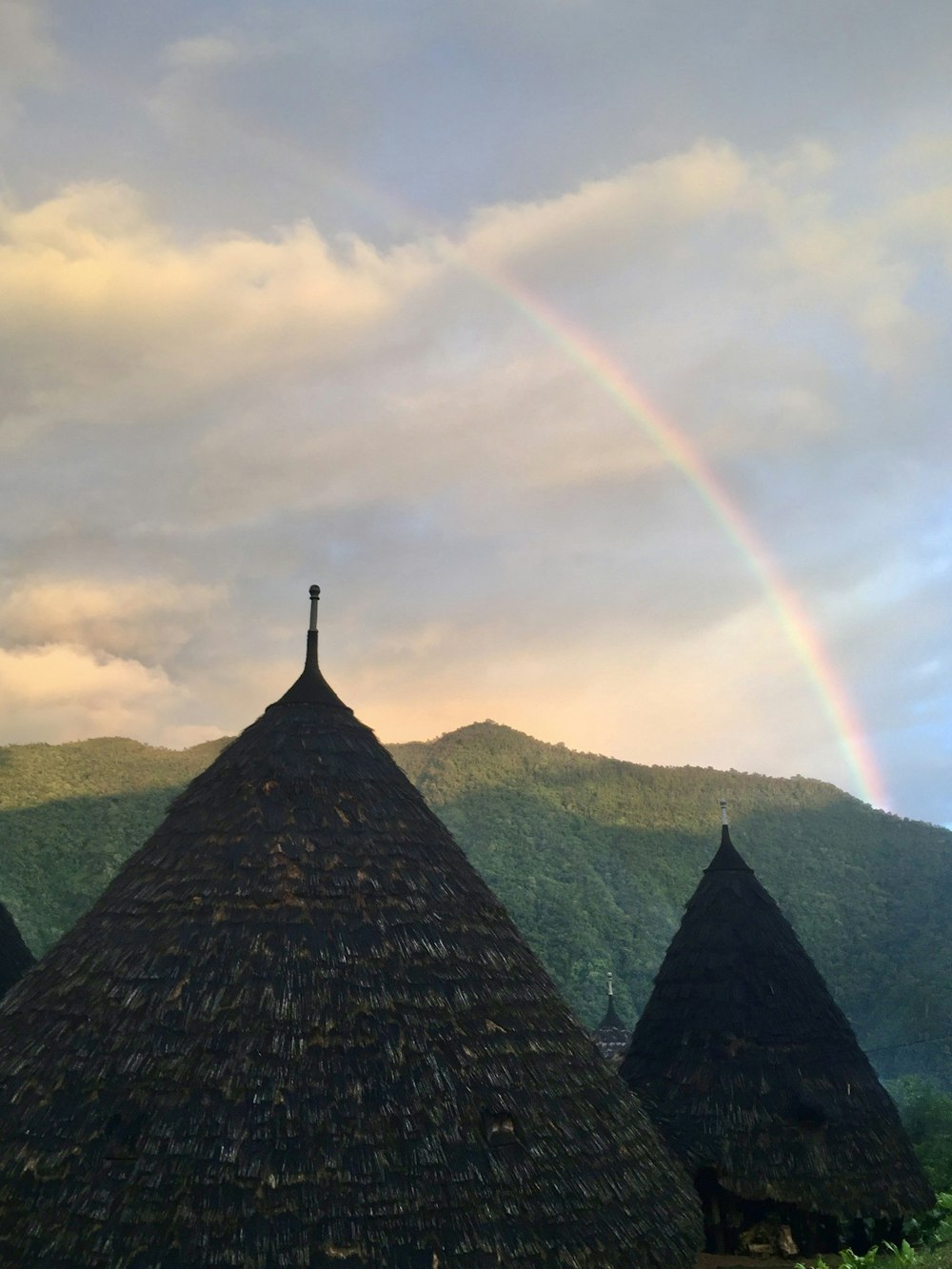 a rainbow in the sky over some huts
