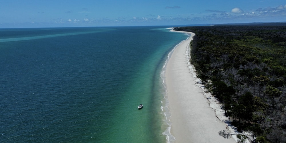 an aerial view of a beach with a boat in the water