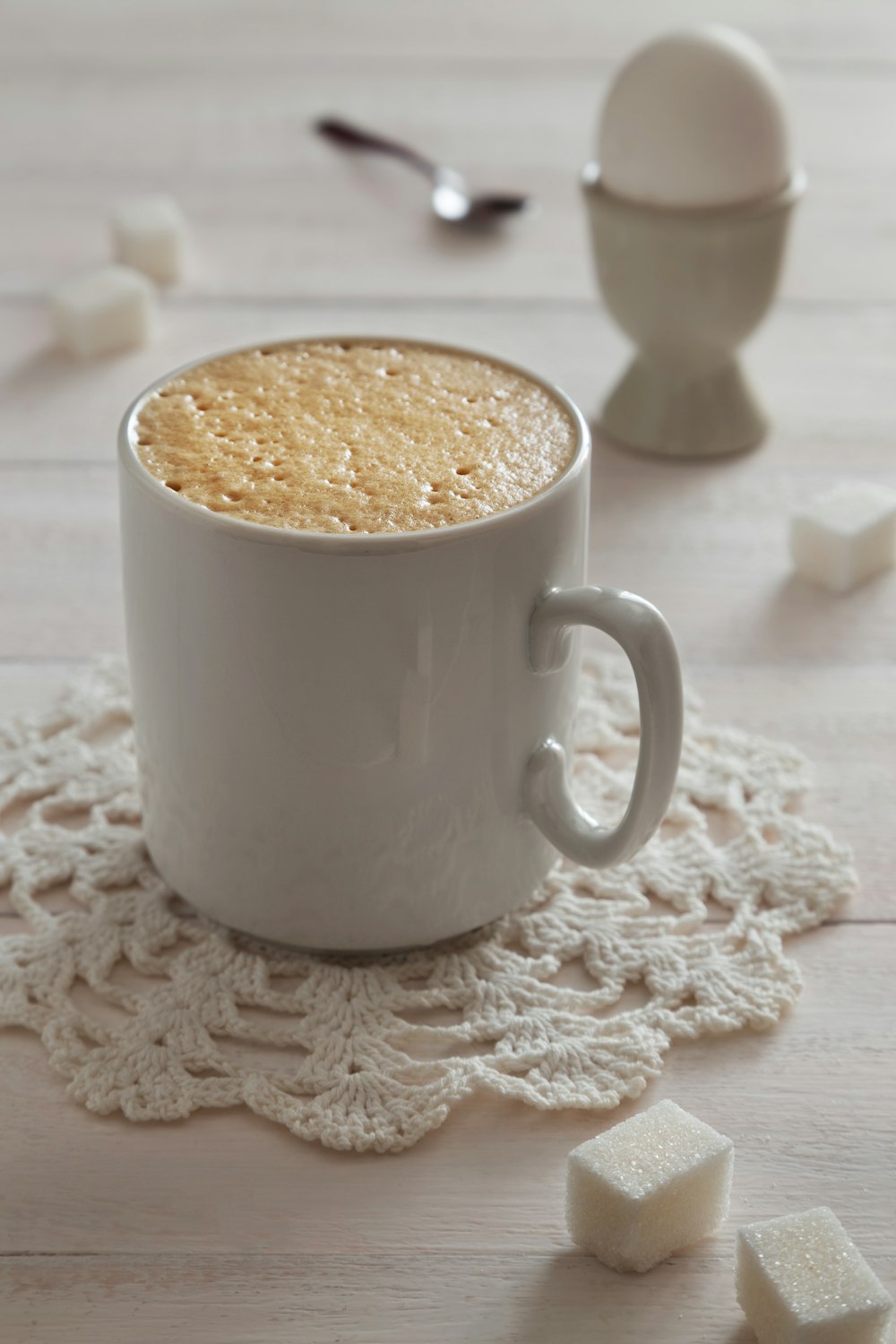a cup of coffee with marshmallows on a doily
